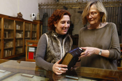 Raquel Jaén, directora del Museo de San Isidoro, y la restauradora de libros Ana Jessen, observan uno de los códices de la biblioteca de la colegiata.