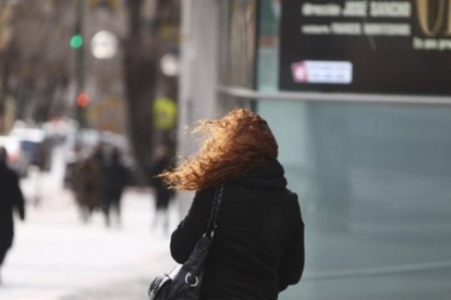 Una mujer afectada por el frío y los fuertes vientos.