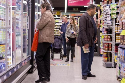 Un grupo de personas comprando en un supermercado.