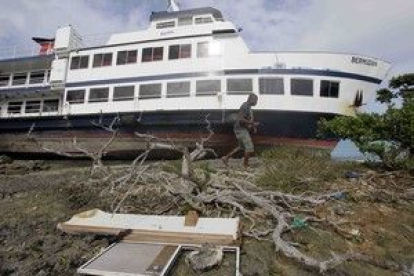 Un hombre camina junto a un barco arrastrado hacia tierra por la fuerza del huracán Igor en Bermuda.