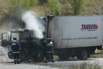 En la foto, dos bomberos lanzan un chorro de agua a la cabina, lugar donde se iniciaron las llamas