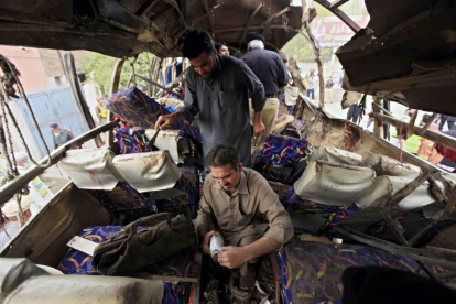 Miembros de las Fuerzas de Seguridad inspeccionan un autobús que ha sufrido un atetado con bomba en Peshawar.