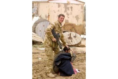 Un soldado norteamericano apunta a uno de los prisioneros en Basra, Irak