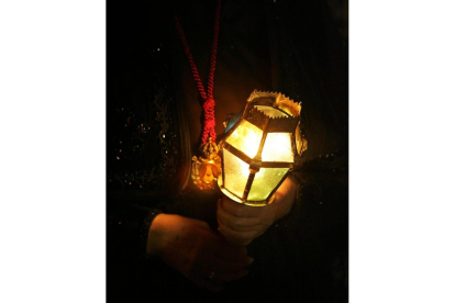 Una mujer con una vela en una procesión de Semana Santa en León