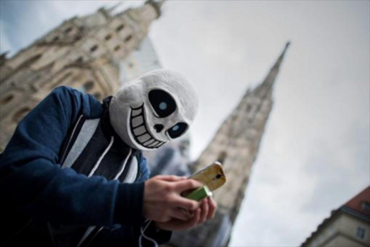 Tras una máscara, un usuario de Pokémon Go juega con la aplicación en las calles de Viena.