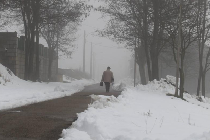 Un hombre camina por una carretera nevada en León.