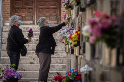 Varias mujeres colocan flores en una tumba del cementerio de Alcalá de Henares. FERNANDO VILLAR