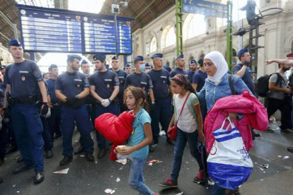 Una familia de refugiados deja la estación más importante del este de Budapest, después de que la policía la cerrara impidiédoles el paso con una valla humana.