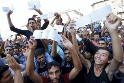 Los refugiados muestran sus billetes de tren con indignación mientras esperan que los trenes vuelvan a circular en la estación de Keleti.