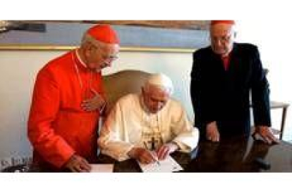 Benedicto XVI firma unos papeles en blanco en la mesa del despacho de Juan Pablo II