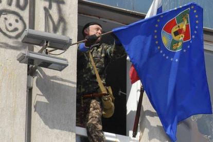Un activista prorruso cuelga una bandera en el edificio del Servicio de Seguridad, en Lugansk.
