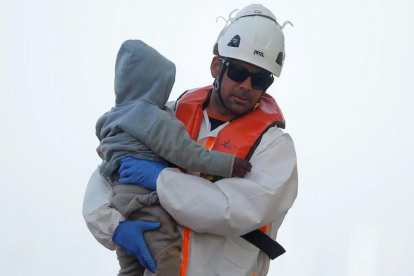 Un sanitario lleva en brazos a un bebé rescatado en una patera, en Málaga.