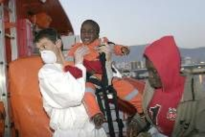 Un miembro de la Cruz Roja desembarca a uno de los bebés que navegaba en una patera en Motril