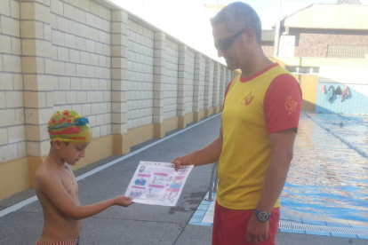 Un niño recibe el díptico donde se recogen las normas básicas para el medio acuático.