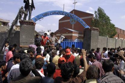 Los cristianos paquistanís y los equipos de rescate se reúnen fuera de una iglesia dañada por un ataque suicida.