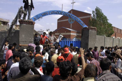 Los cristianos paquistanís y los equipos de rescate se reúnen fuera de una iglesia dañada por un ataque suicida.