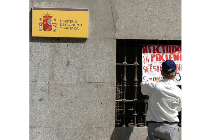 Un hombre coloca una pancarta en la fachada del Ministerio de Hacienda VÍCTOR LERENA