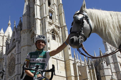 Miguel Ángel Benito posa con la elástica de su equipo, el Caja Rural, delante de la Catedral de León, mientras acaricia a un caballo