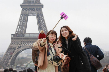 Turistas utilizando del palo para hacerse selfis en París.