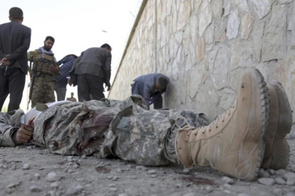 Militares inspeccionan el cadáver de un miliciano en la sede del Ministerio del Interior afgano, en Kabul.