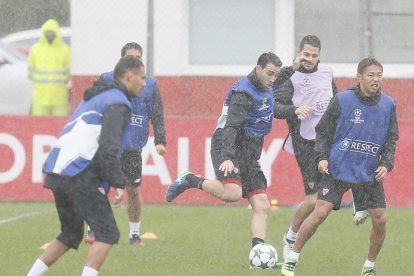 Los jugadores del Sevilla durante el entrenamiento realizado ayer, en el que no dejó de llover. J. M. VIDAL