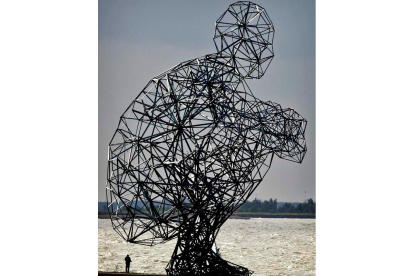 Imagen de la escultura gigante de un hombre agachado situada en una presa de Lelystad, Holanda