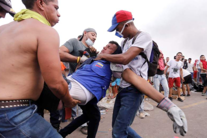 Un hombre herido es ayudado, ayer, en Ureña, donde se esperaba ayuda humanitaria. DEIBISON TORRADO