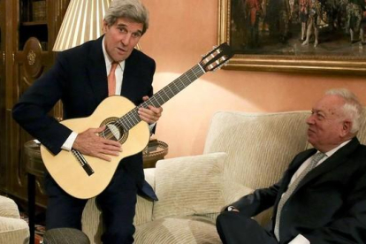 Kerry con la guitarra española que le ha regalado Margallo, sentado en el sofá, esta tarde en el Palacio de Viana, en Madrid
