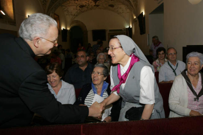 El obispo de León, Julián López, saluda a una de las misioneras durante su llegada al Salón del Pendón.