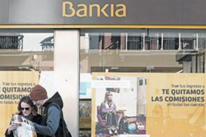 Unos turistas en Sevilla, ante una sede de Bankia.