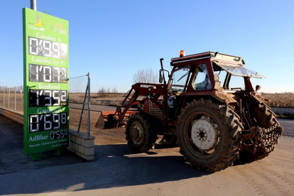 Un tractor permanece apostado junto al cartel de precios de la gasolinera de una cooperativa.