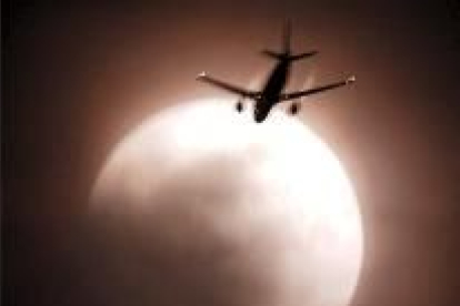 En la fotografía, un avión pasa junto a la luna eclipsada