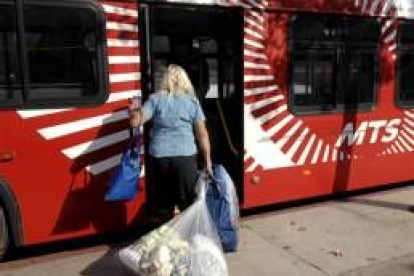 Una mujer evacuada sube a un autobús con sus pertenencias
