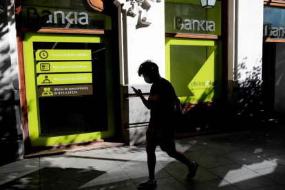 Una persona camina por el centro de Madrid delante de una sucursal de Bankia. JUAN CARLOS HIDALGO