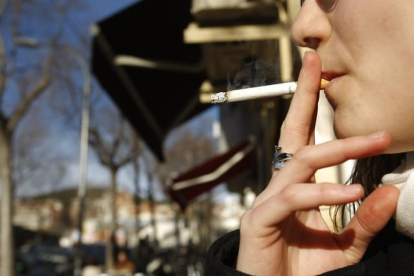 Una mujer fuma en la calle.