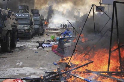 Tiendas de campaña arden junto a vehículos blindados de la policía en la acampada de los seguidores de Mursi en la plaza de Rabea al Adauiya en El Cairo.