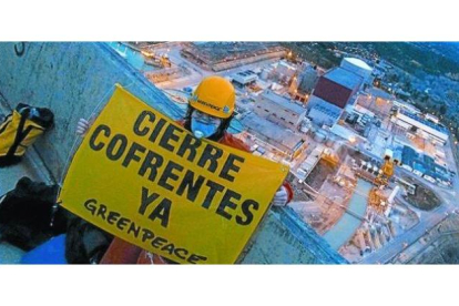 Un activista de Greenpeace, con un cartel en una de las torres de refrigeración de Cofrentes.
