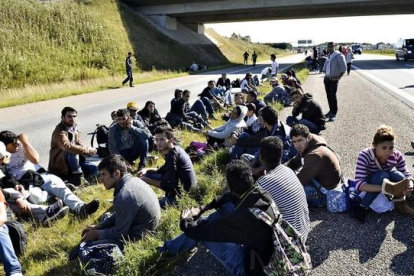 Un grupo de refugiados descansan en medio de una autopista en el sur de Dinamarca.