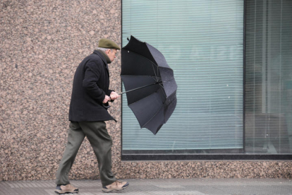 Un hombre sujeta su paraguas durante una tacha de viento. DL