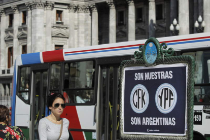 Una mujer, junto a un cartel de apoyo a la expropiación de la petrolera YPF en Buenos Aires.
