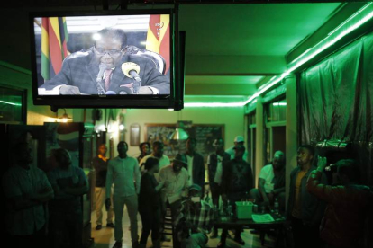 Un grupo de personas escuchan el mensaje televisado de Robert Mugabe. KIM LUDBROOK