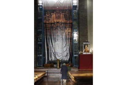 Una feligresa camina hacia el altar del Santuario, cubierto de andamios