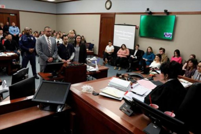 Larry Nassar, de pie, escucha la sentencia de la juez, ayer, en Michigan. Bajo esta foto algunas de sus víctimas.