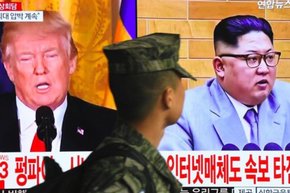 Un soldado surcoreano pasa frente a un televisor en Seúl mientras aparecen en la pantalla Donald Trump y Kim Jong un.