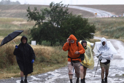 La lluvia sorprende a unos peregrinos a su paso por León.