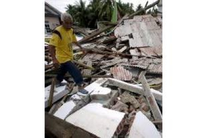 Un superviviente del terremoto camina entre los escombros de su casa