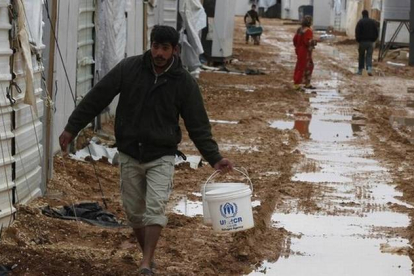 Refugiados sirios en el campo de Al Zaatari (Jordania) que la lluvia ha convertido en un barrizal.