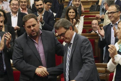El presidente de la Generalitat, Artur Mas, estrecha la mano del lider de ERC, Oriol Junqueras, ante el aplauso de sus compañeros de partidos, tras la aprobación, hoy en el pleno del Parlamento de Cataluña, de una resolución pactada por los cuatro partido