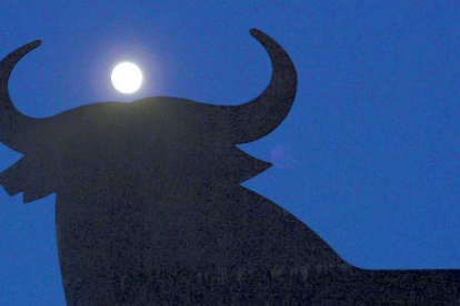 La luna tras la silueta del toro de Osborne en el Puerto de Santa María. MANU FERNÁNDEZ/AP