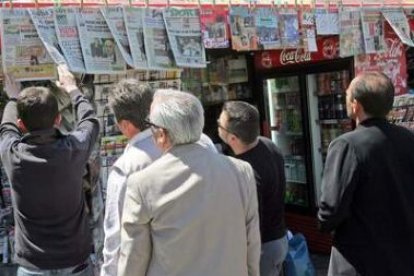 Un grupo de personas lee las portadas de los periódicos en un quiosco de Atenas.